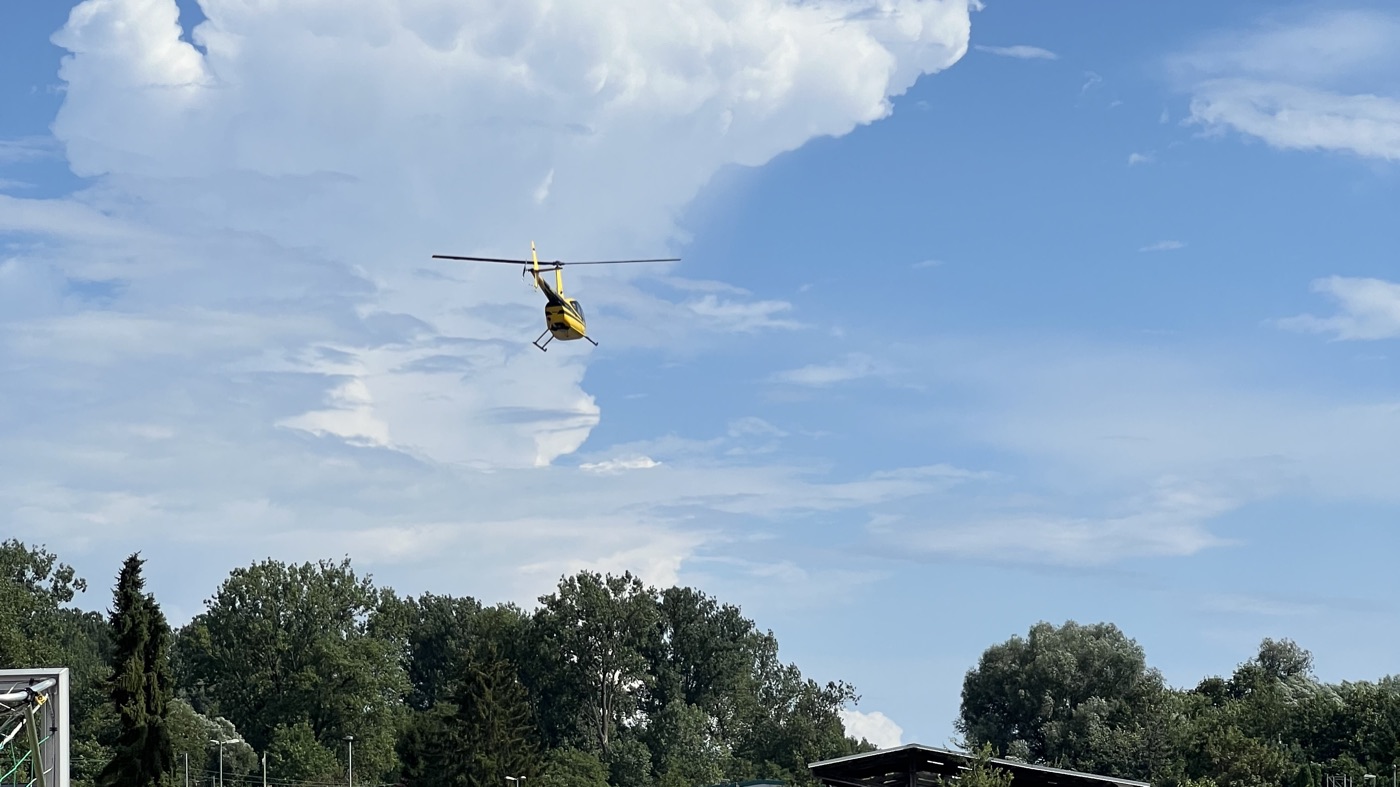 Robinson R44 von Airkraft Helicopter im Flug vor einer Wolke